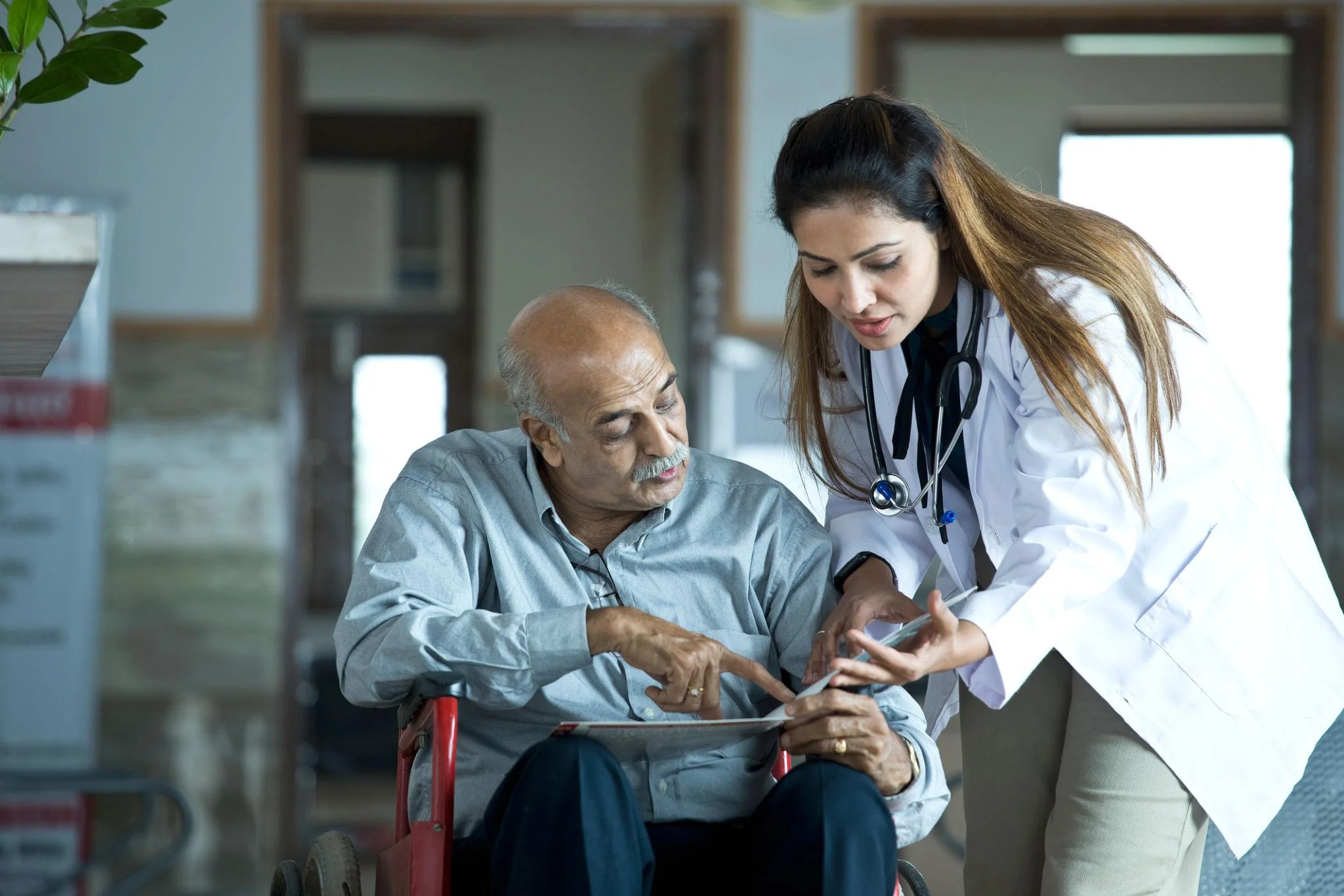 A clinician in conversation with an older man seated at home