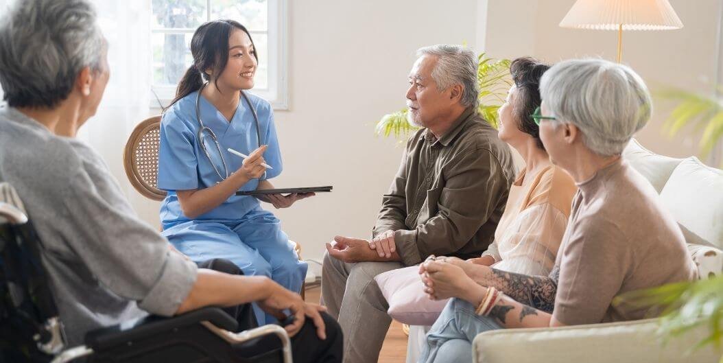 A care worker in conversation with an older man in a sunlit room at home